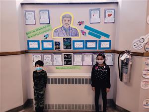 Photo shows two Jefferston students standing in front of wall display with colored picture & info about Neil DeGrasse Tyson